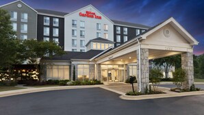 A Hilton Garden Inn with a stone entrance and a clear sky.
