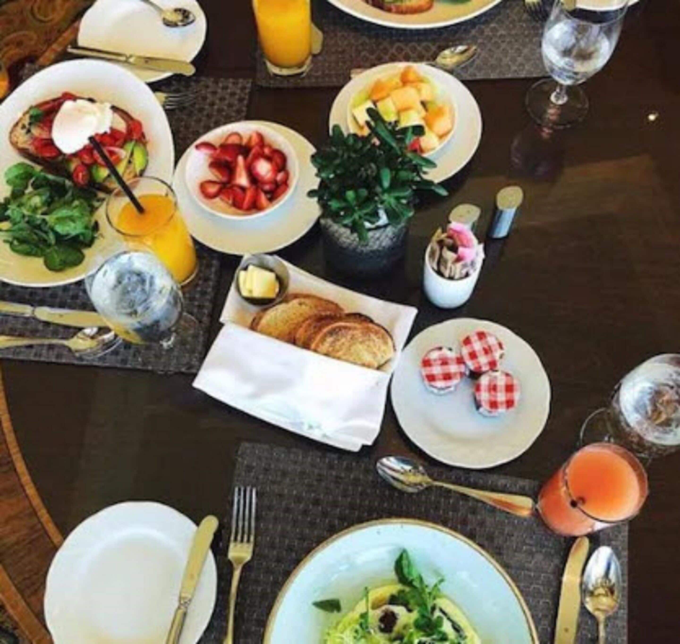 A breakfast setting with various dishes, drinks, and utensils on a table.