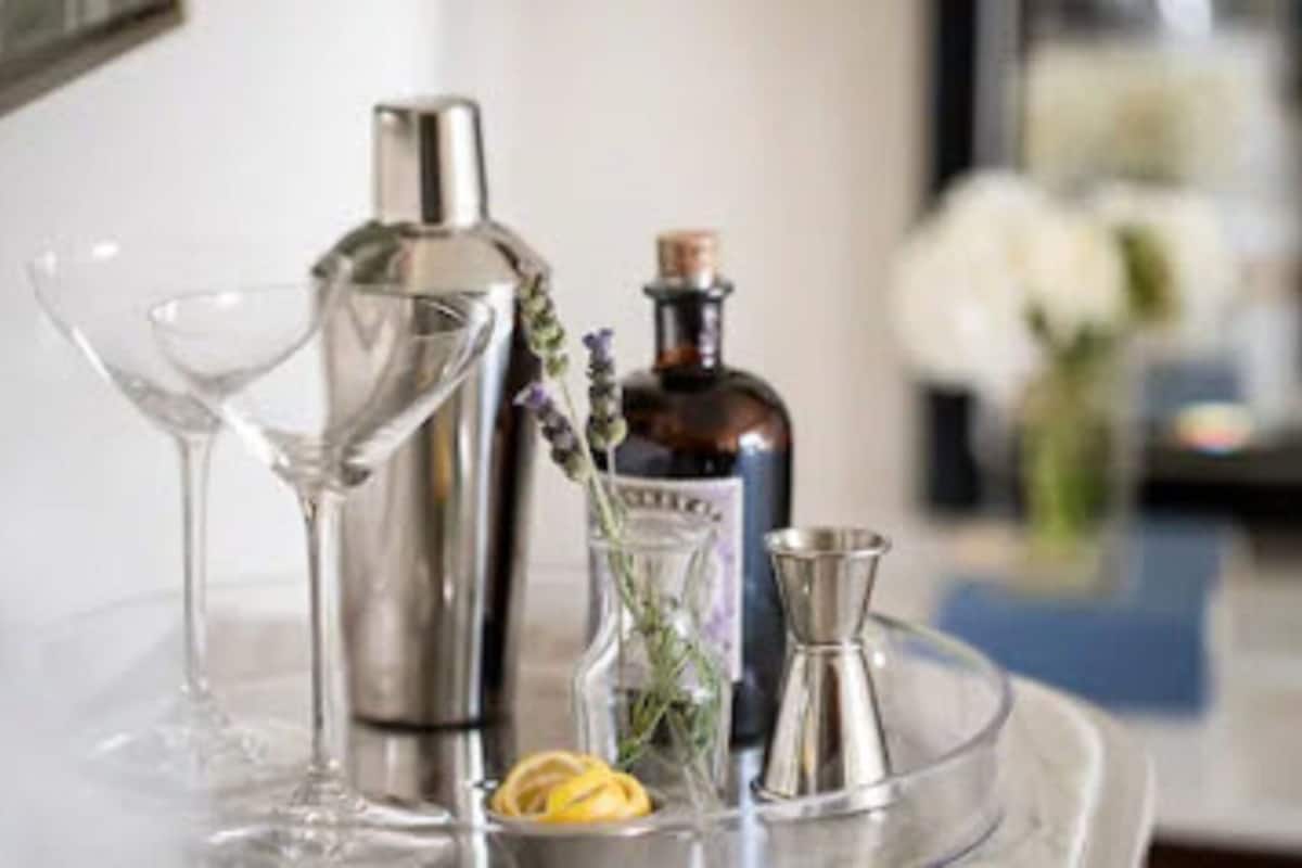 A bar area with a martini glass, a bottle, a small pitcher, and a glass with a lemon slice.