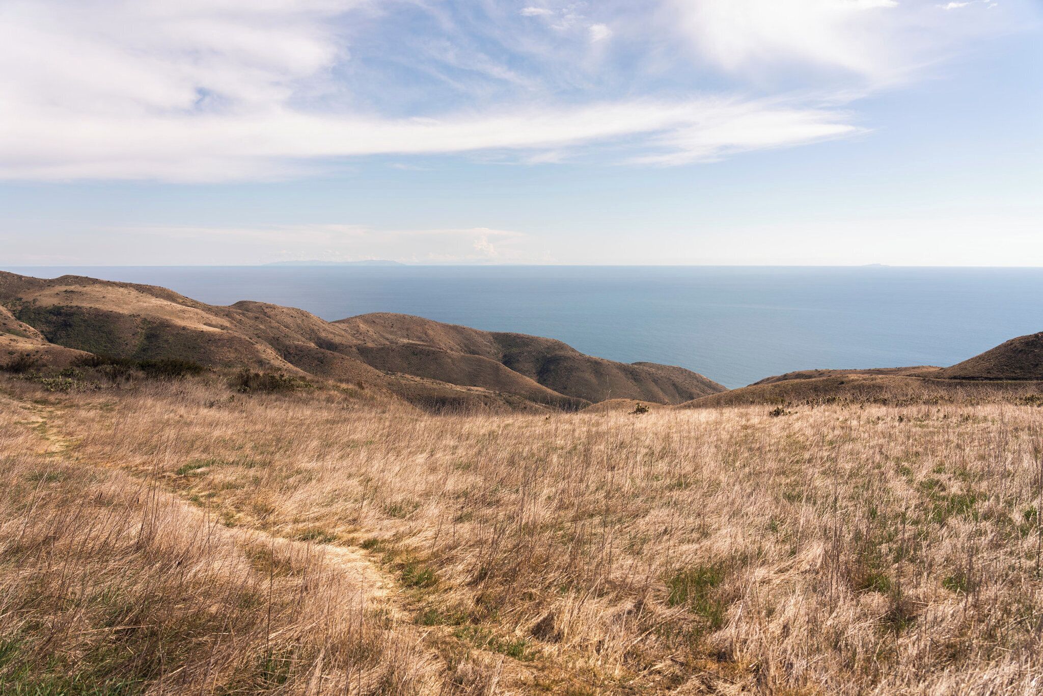 A hilly landscape with a clear view of the ocean.