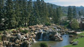 A landscaped garden with a pond, cascading waterfalls, and a gazebo.