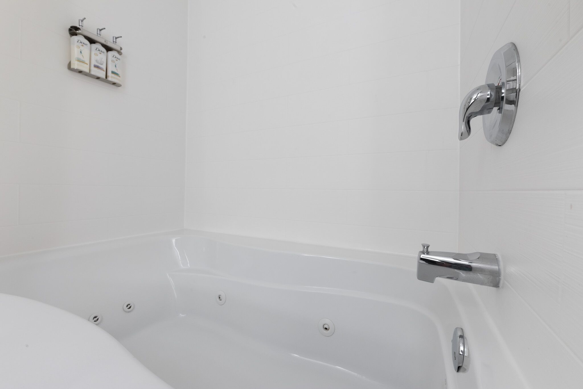 A modern bathroom with a freestanding bathtub, a wall-mounted faucet, and a soap dispenser.