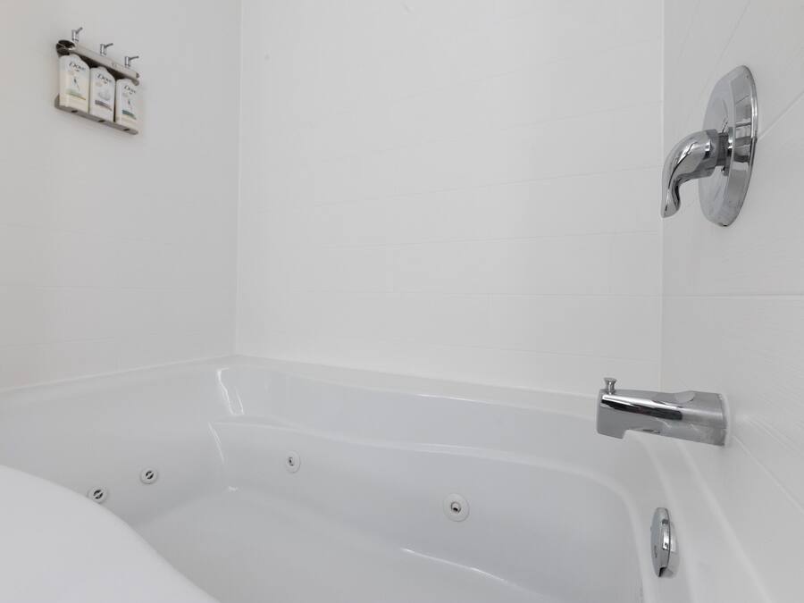 A modern bathroom with a freestanding bathtub, a wall-mounted faucet, and a soap dispenser.