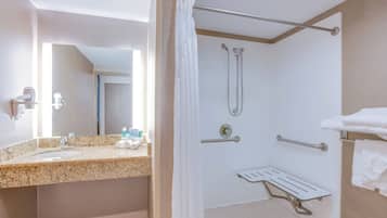Un bagno d'hotel con lavabo in granito, doccia con soffione manuale e porta asciugamani.