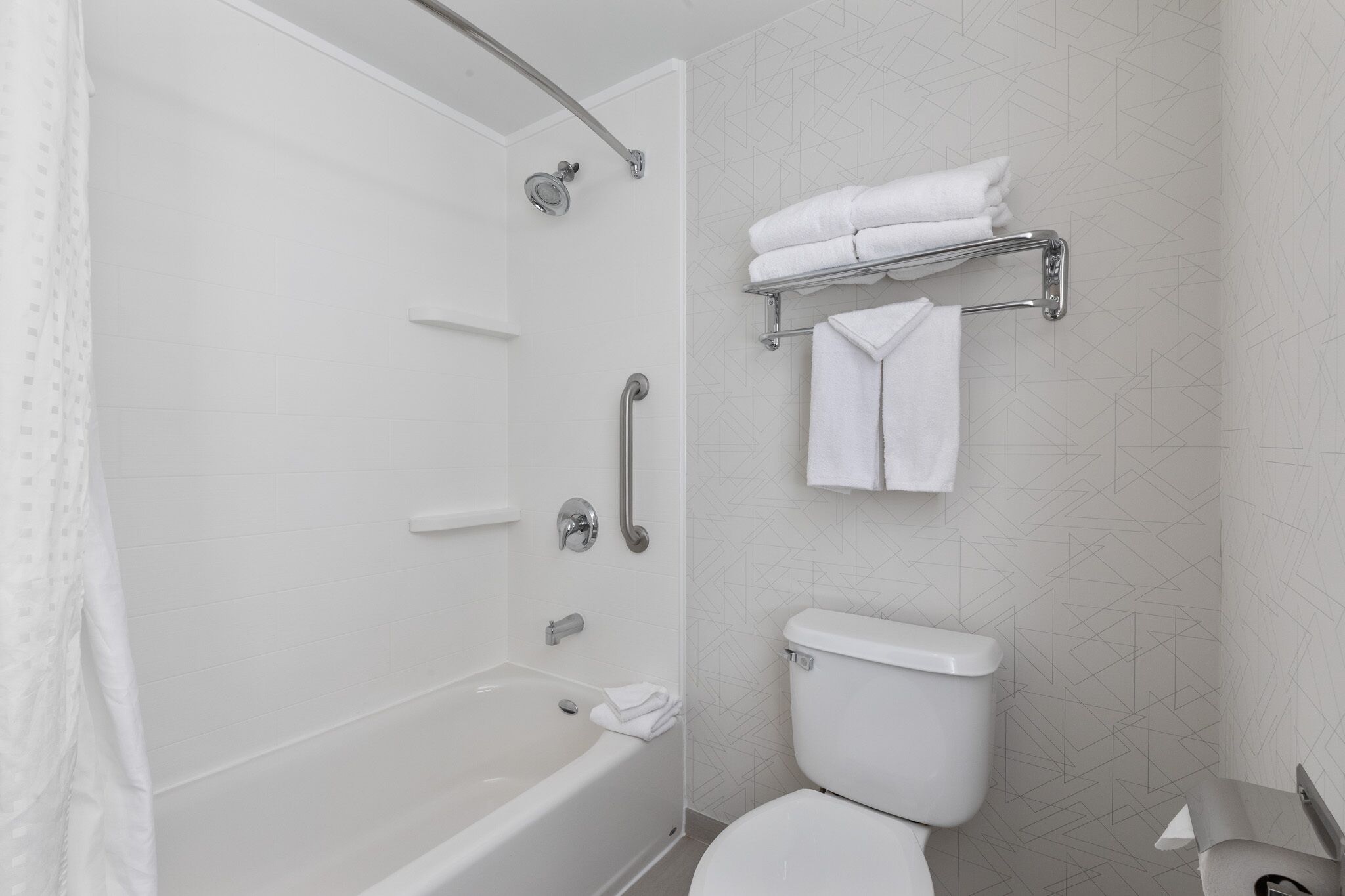 A modern bathroom with a bathtub, toilet, and towel rack.