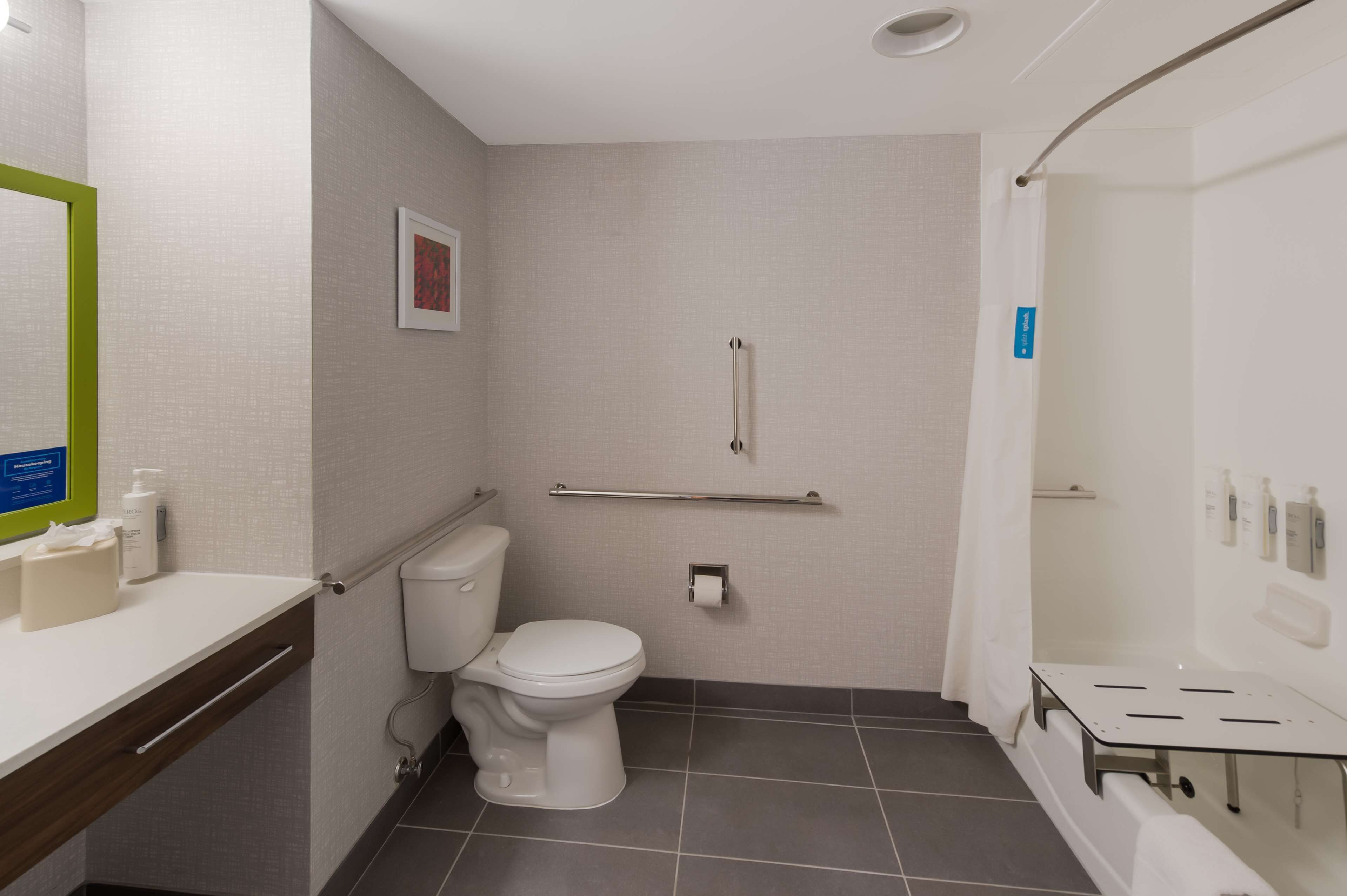 Een moderne badkamer met toilet, douche en wastafel.
