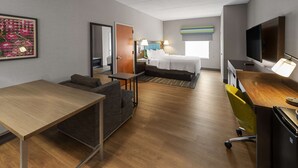 A hotel room with a bed, a desk, a chair, a TV, and a painting on the wall.