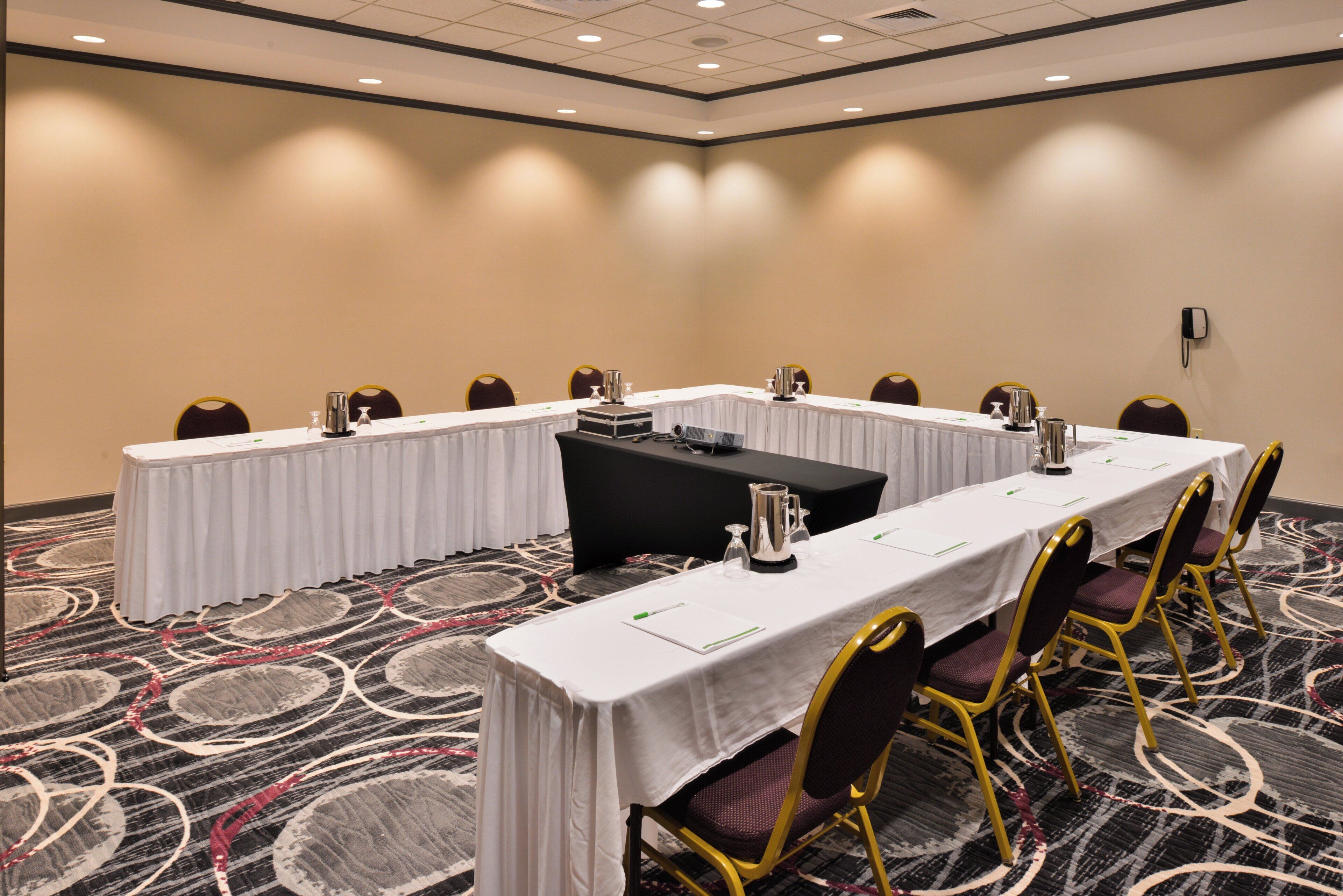 Un salón de conferencias con una larga mesa, sillas y un proyector.