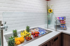A self-service breakfast bar with a variety of fruits, yogurts, and cereals.
