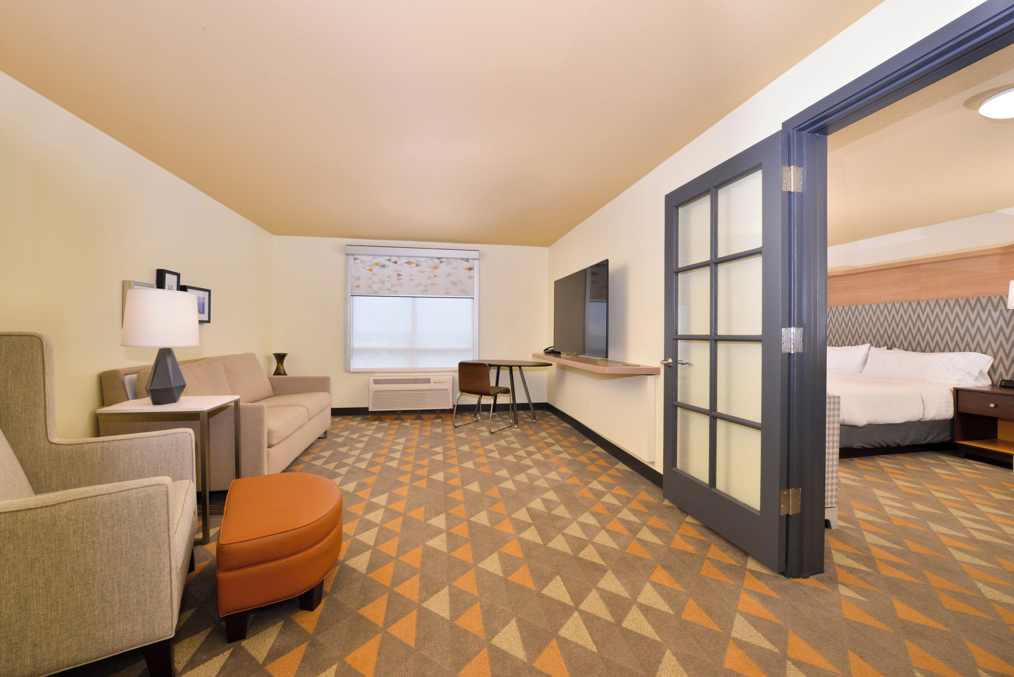 A hotel room with a bed, a desk, a chair, a sofa, and a television.