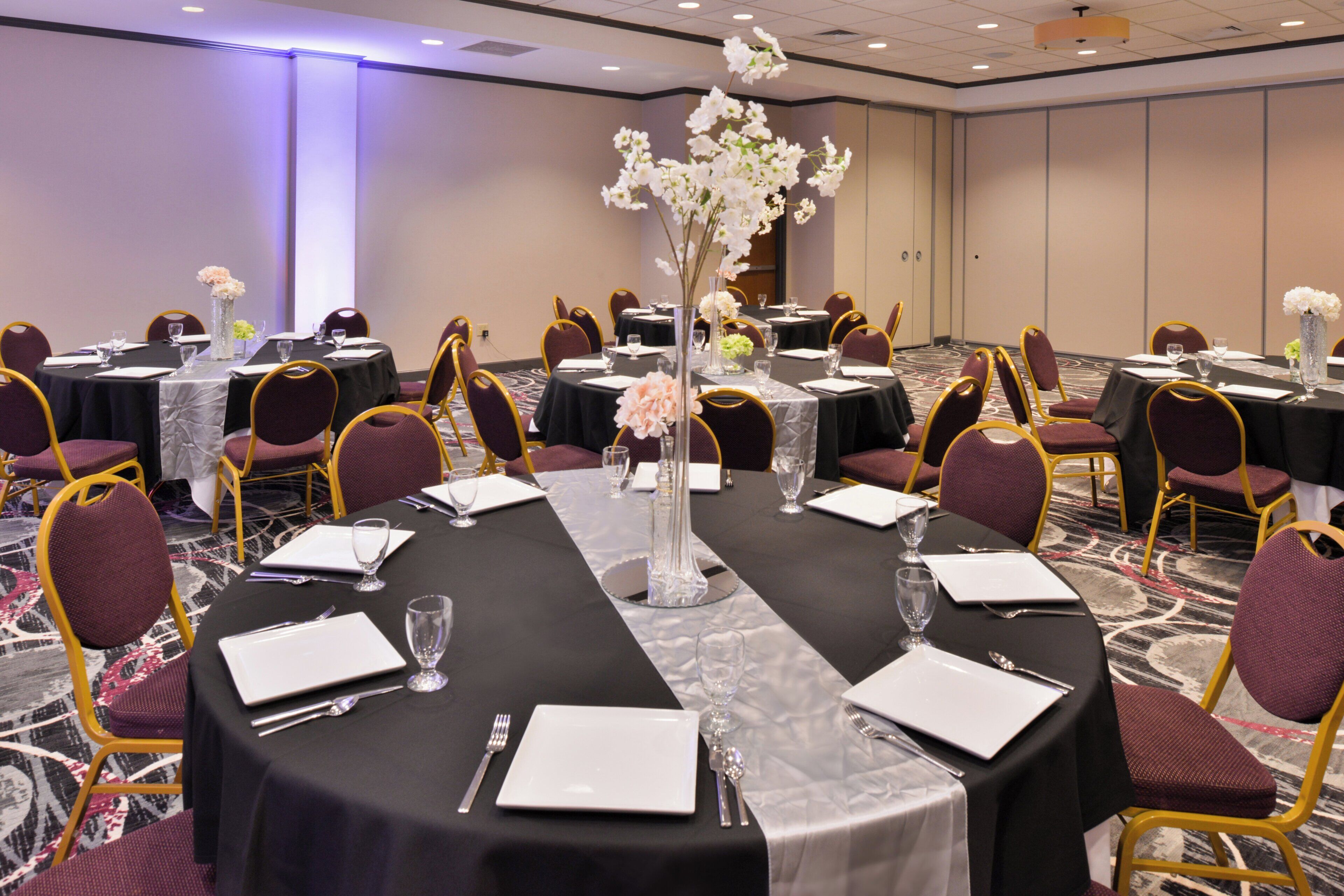 A conference room with round tables, chairs, and floral centerpieces.