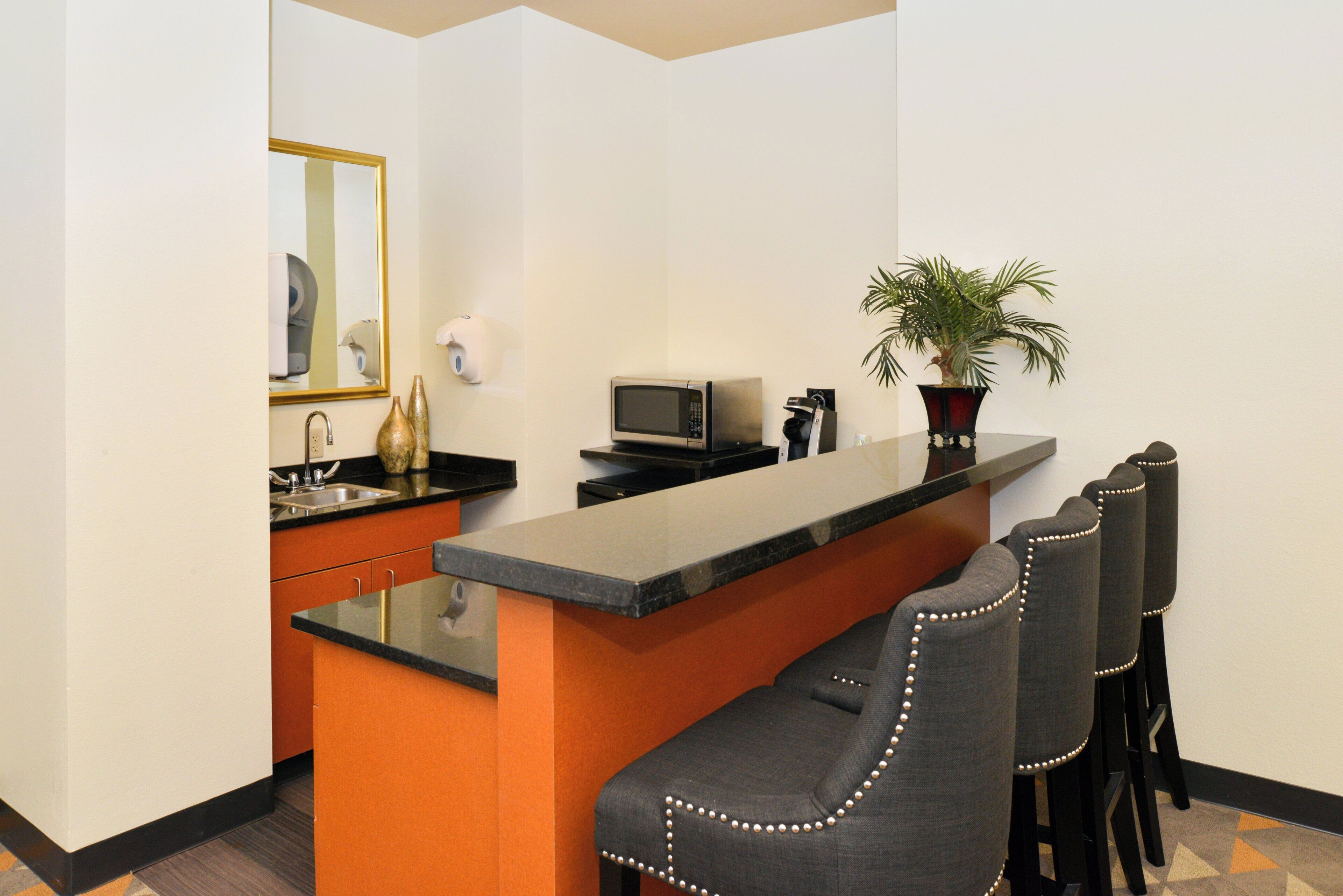 A compact kitchen with a central island, a microwave, a sink, and a potted plant.