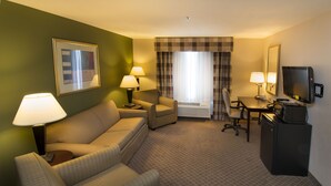 Hotellihuone, jossa on sohva, nojatuoli, työpöytä, televisio ja kaksi lamppua.