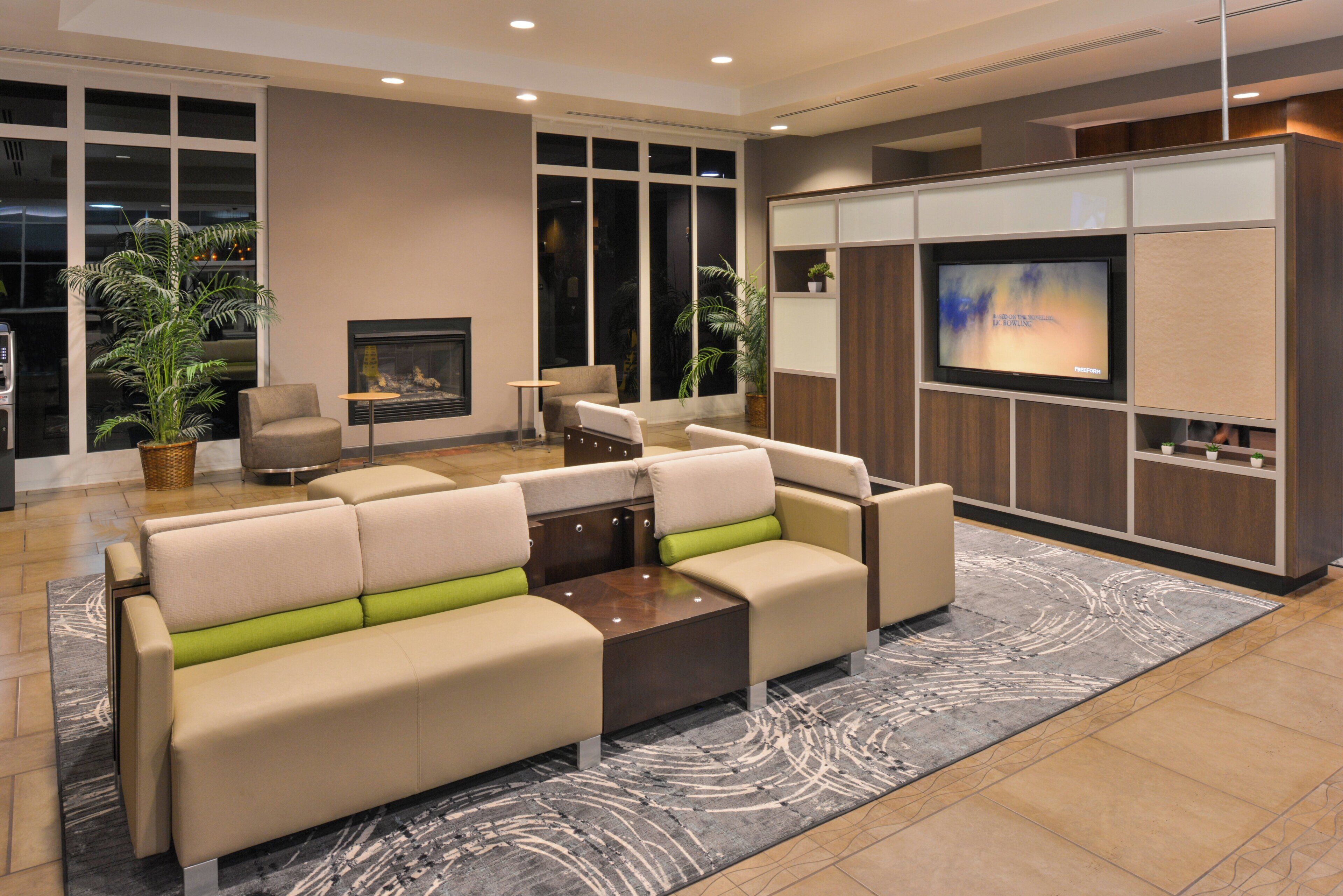 A modern living room with a sectional sofa, a fireplace, and a television.