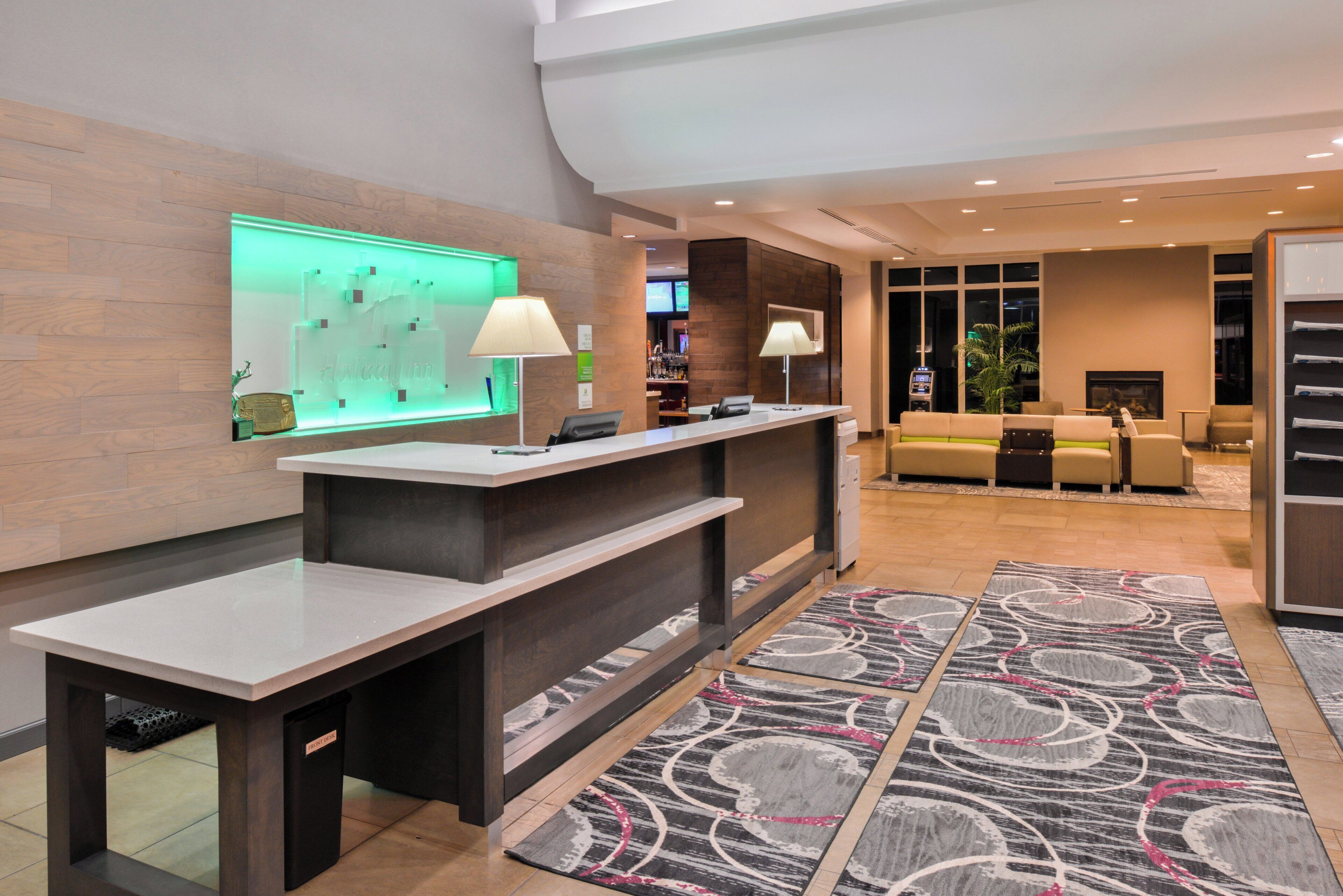 A hotel lobby with a reception desk, a bar area, and a seating area with sofas.