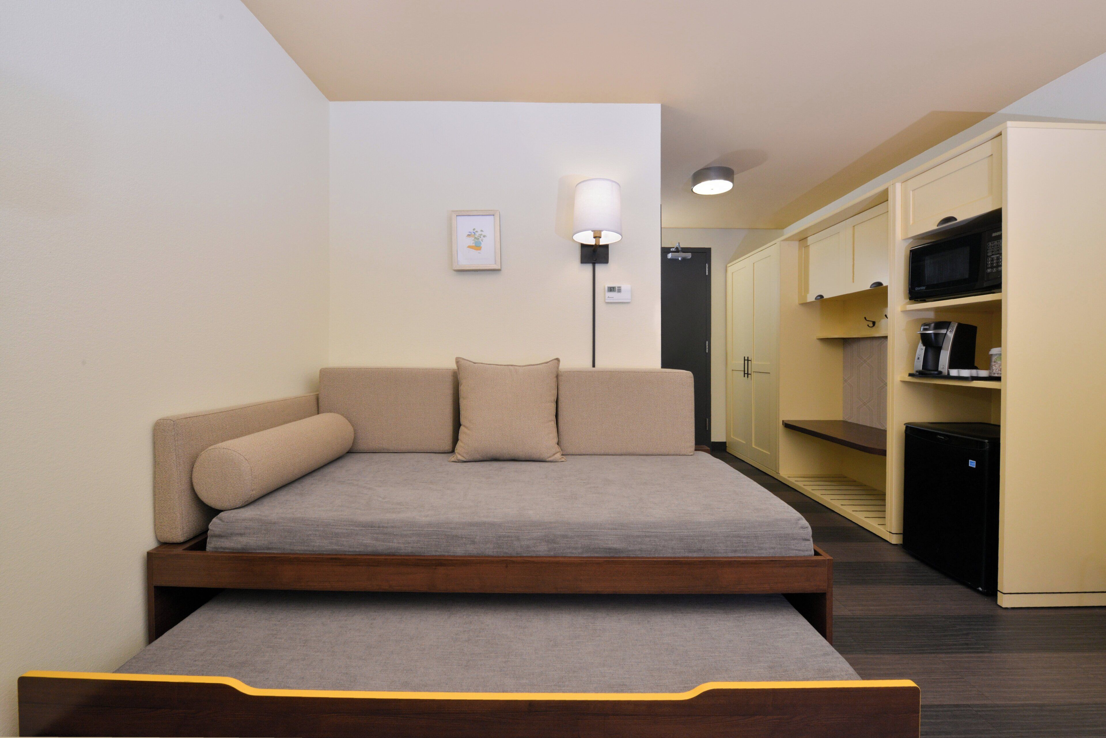 A compact room with a bed, a bedside table, a lamp, and a wardrobe.