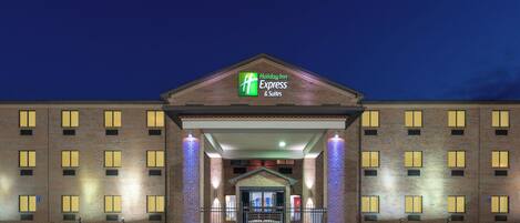 Un bâtiment de la chaîne Holiday Inn Express & Suites, avec une façade en briques, de nombreuses fenêtres et une entrée bien éclairée.