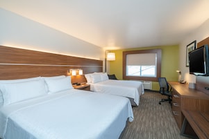 Una habitación de hotel con dos camas, un escritorio, una silla, un televisor y una ventana.