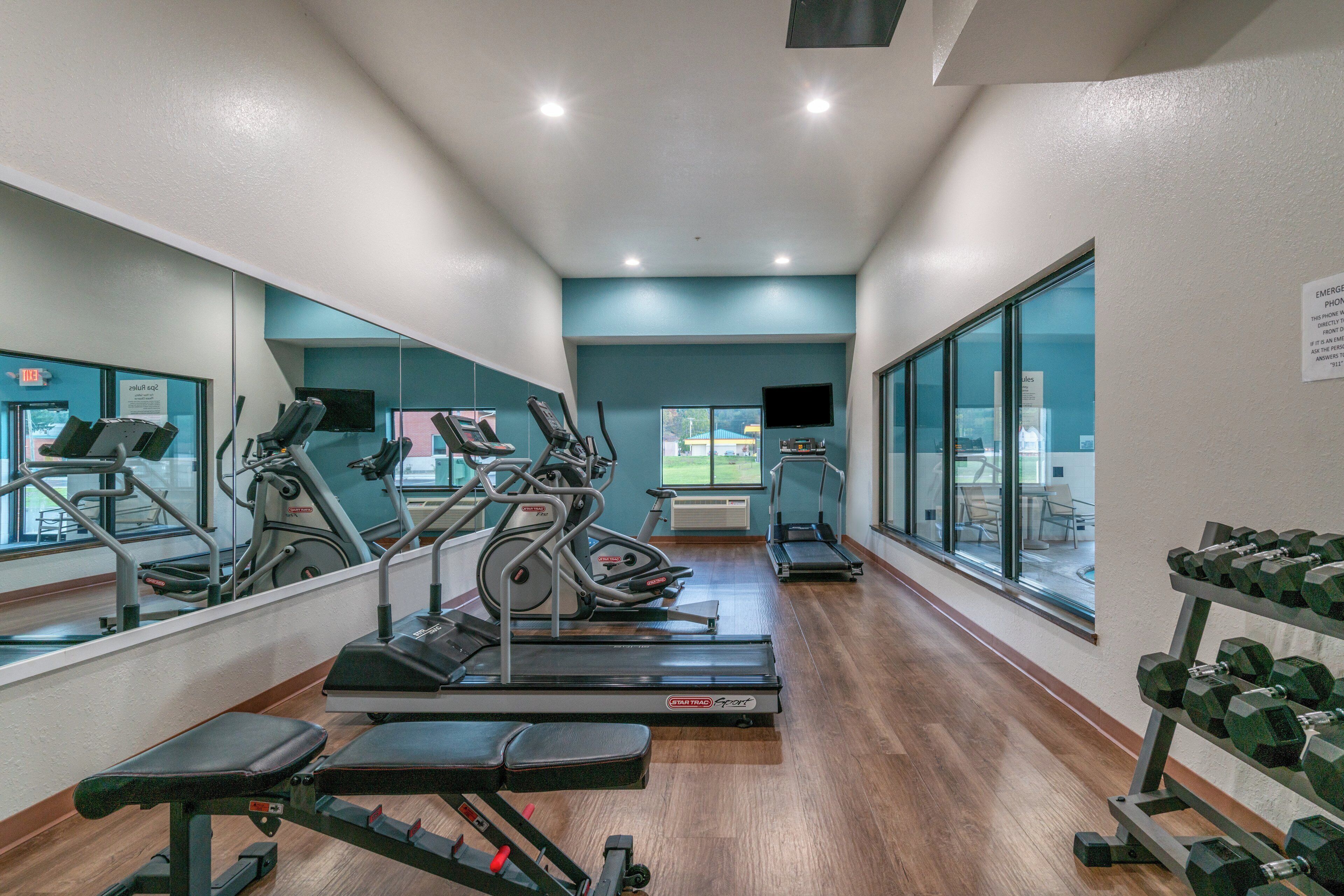 A gym with cardio machines, weight benches, and dumbbells.
