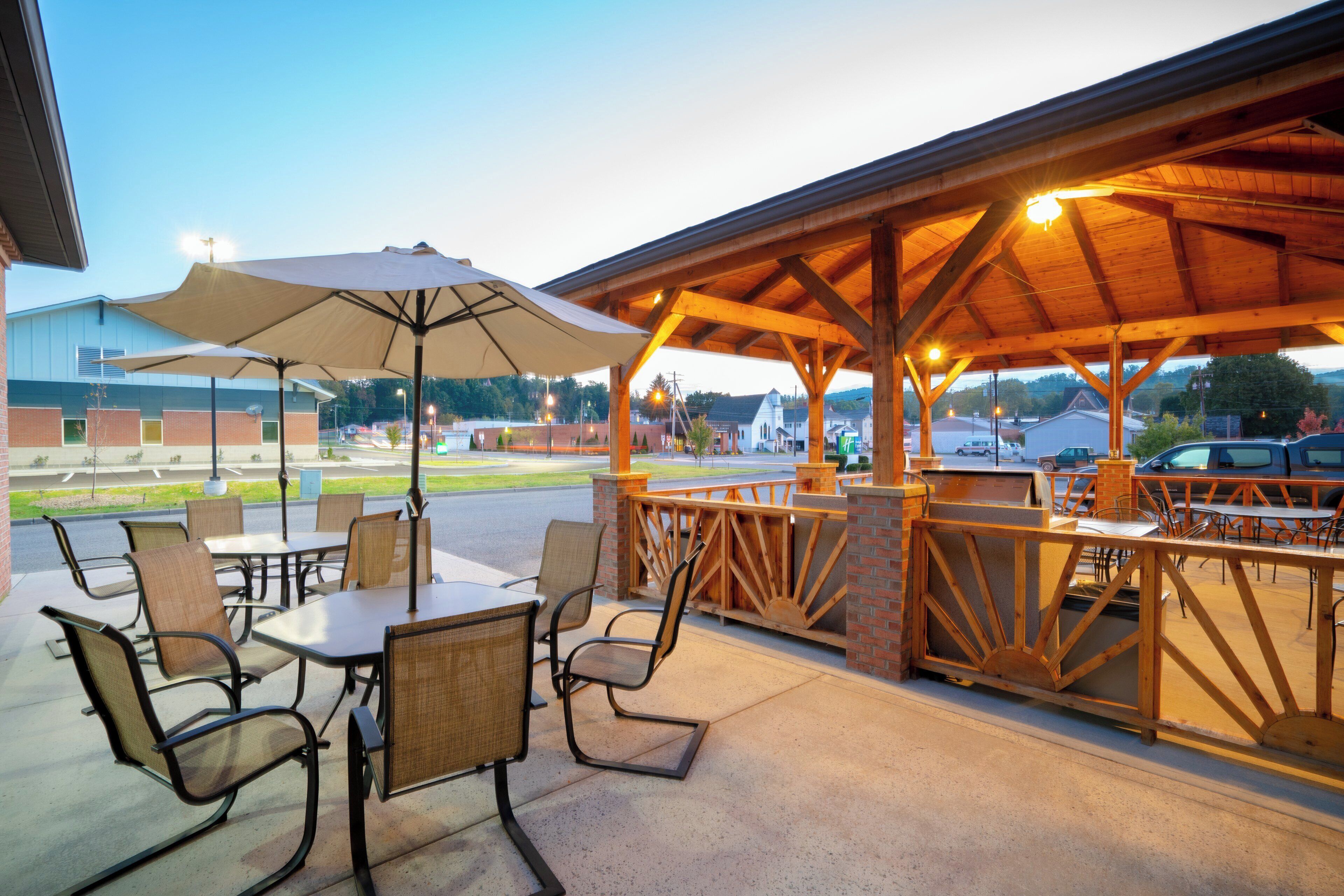 An outdoor patio area with tables and chairs, a covered seating area, and a view of the surrounding landscape.