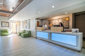 A hotel reception area with a modern design, featuring a reception desk, seating area with green sofas, and a large window providing natural light. - Holiday Inn Express Hotel & Suites ELKINS by IHG (Elkins)