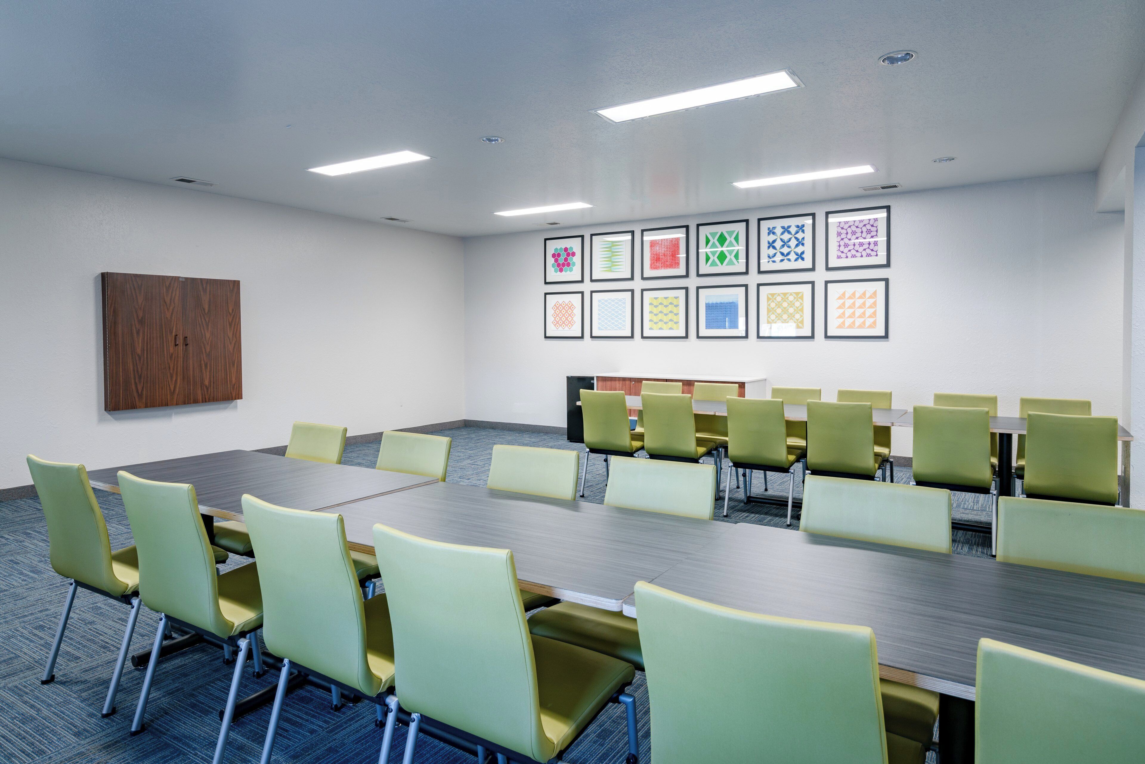 A conference room with a long table, multiple chairs, and framed artwork on the wall.