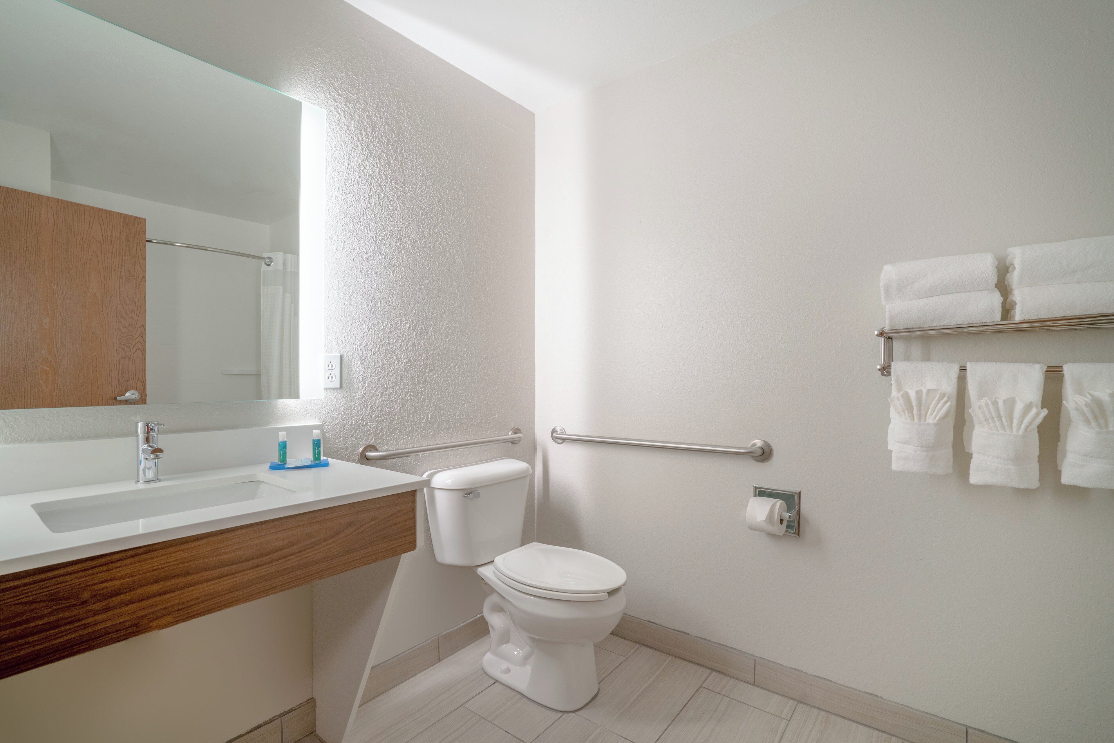 Een moderne badkamer met een witte wastafel, toilet en spiegel.