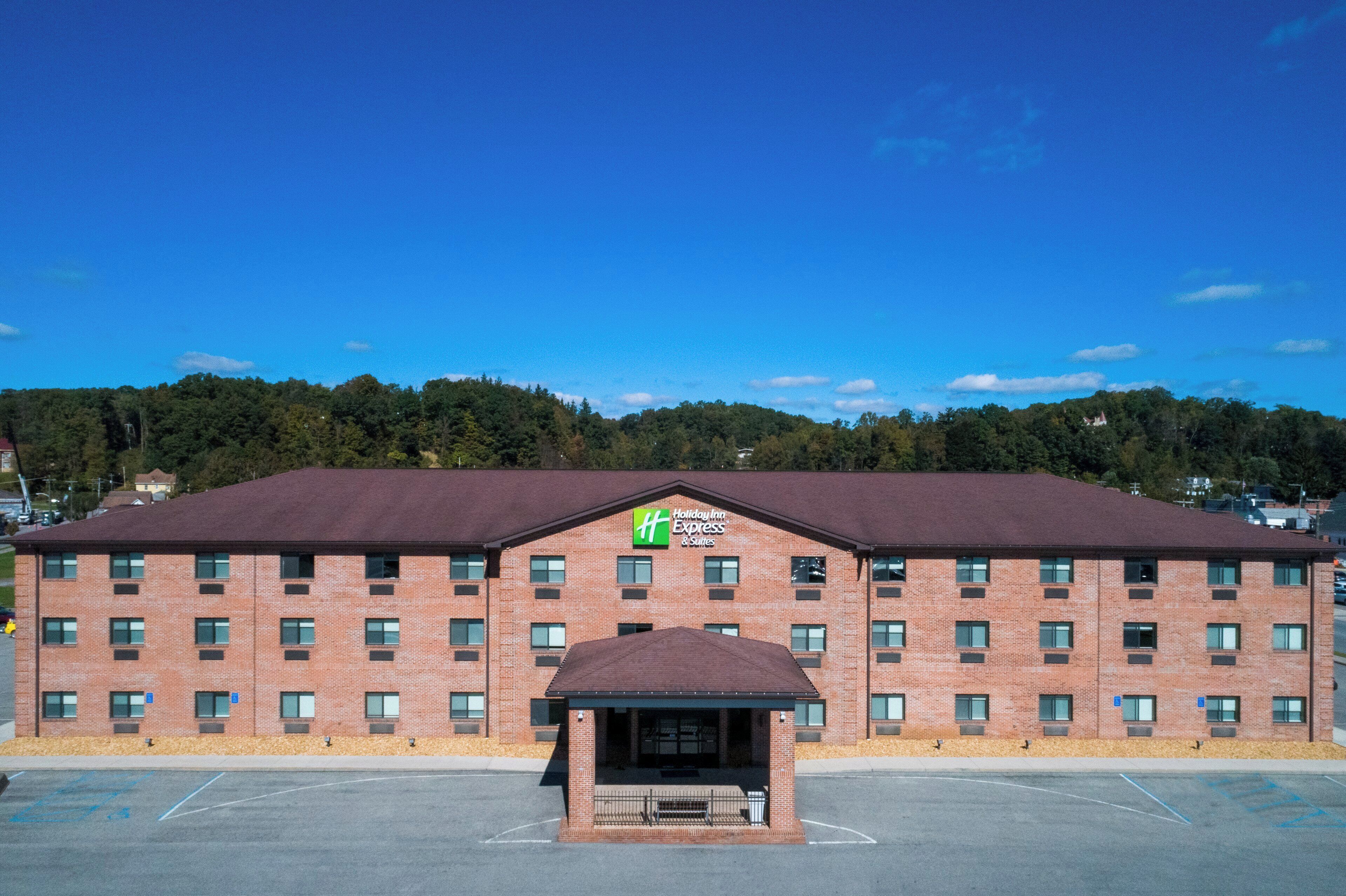 A Holiday Inn Express & Suites with a brick facade, multiple windows, and a parking lot in front.