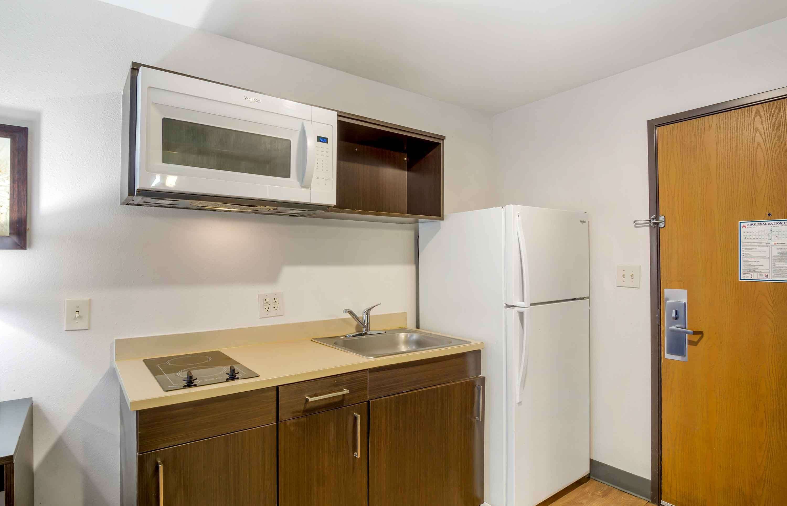 A compact kitchen with a microwave, sink, and refrigerator.