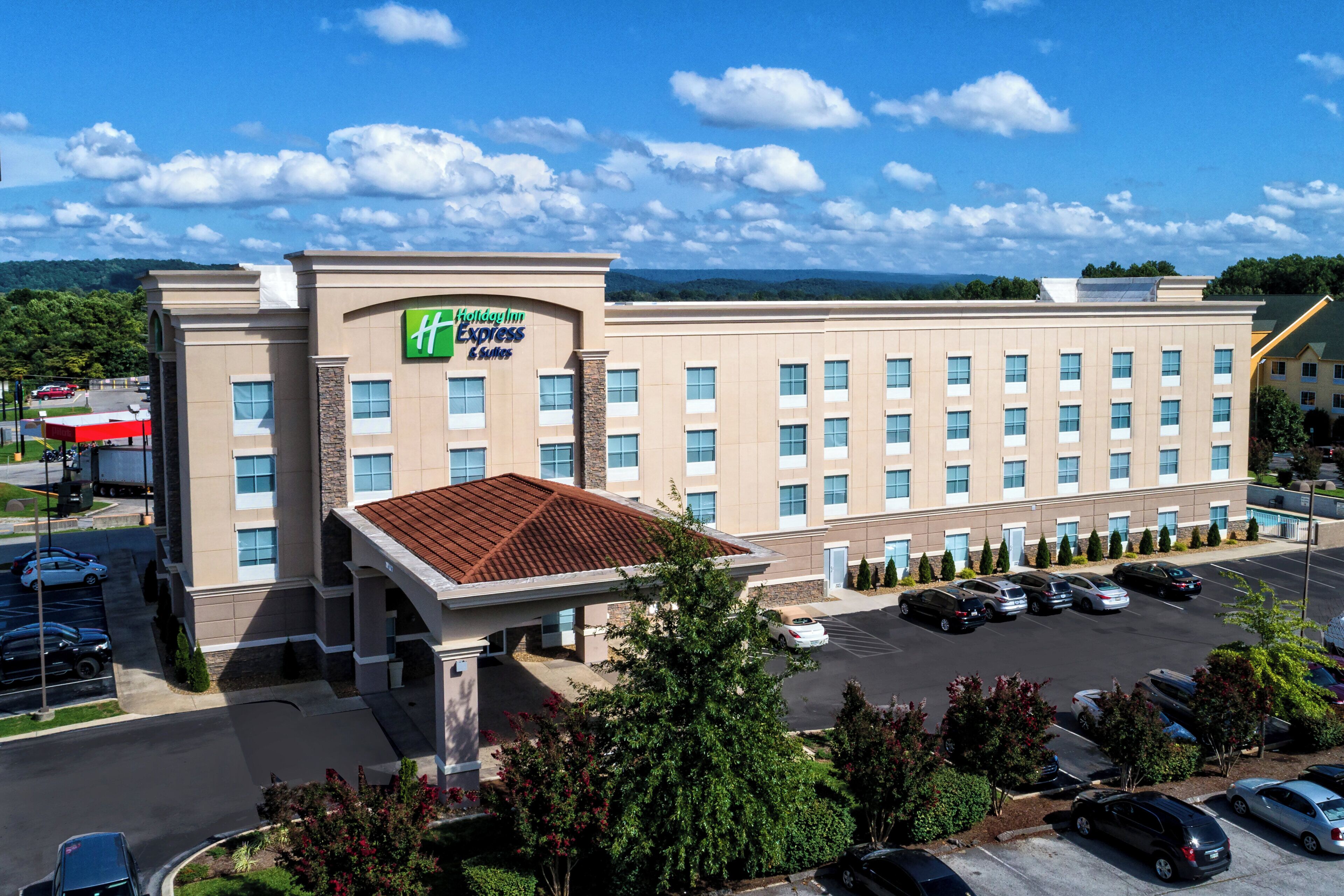 Ett Holiday Inn Express & Suites-hotell med en parkeringsplats och utsikt över det omgivande området.