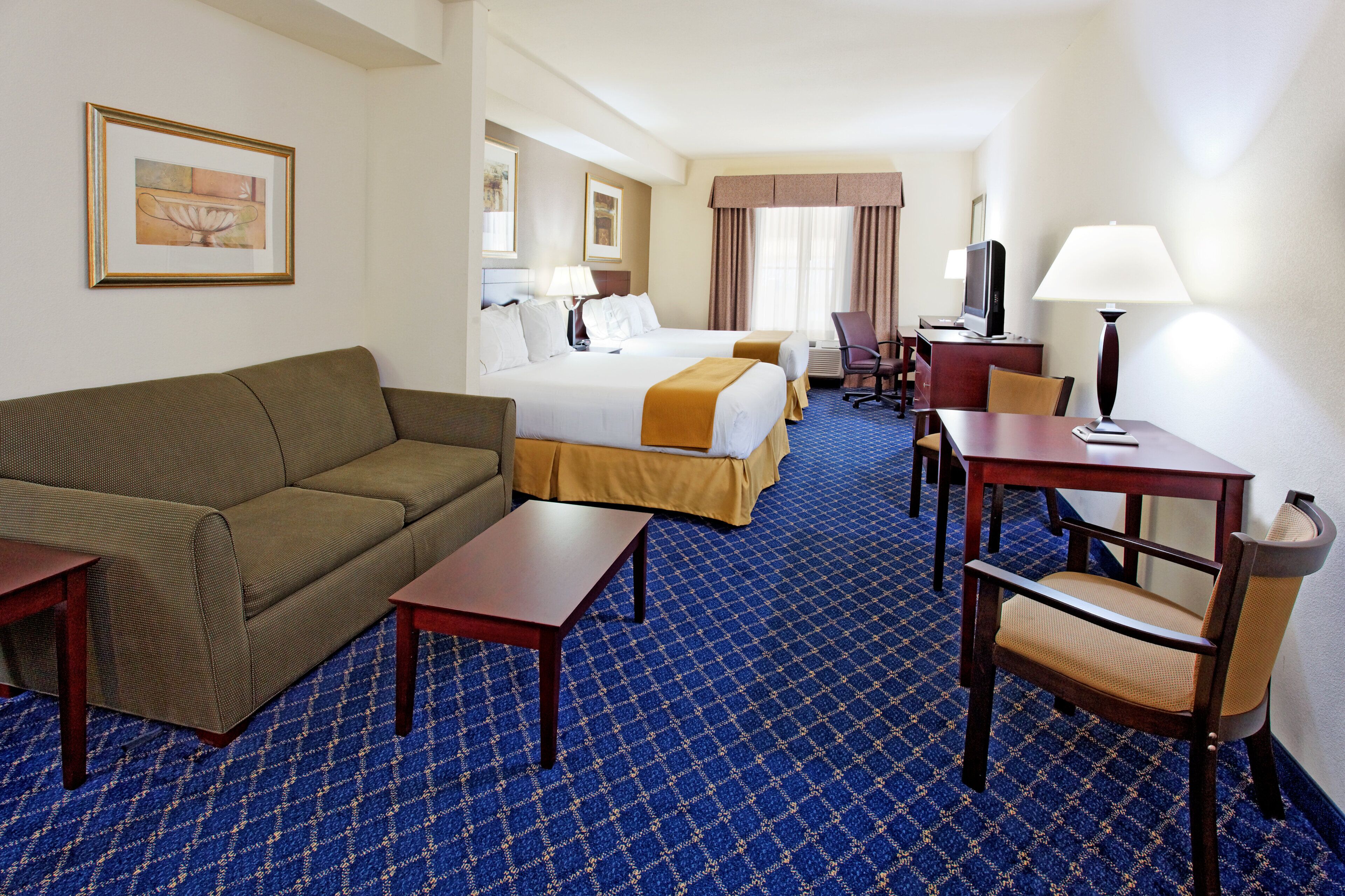 Een hotelkamer met een bed, een bank, een bureau, een stoel en een televisie.
