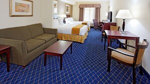 Ein Hotelzimmer mit Bett, Sofa, Schreibtisch, Stuhl und Fernseher.