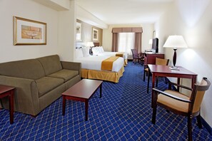 Quarto de hotel com cama, sofá, escrivaninha, cadeira e televisão.