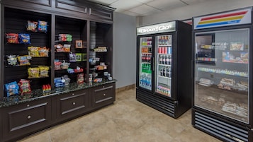 Mostrador con varios tipos de papas fritas y aperitivos, un dispensador refrigerado para bebidas y un congelador con productos congelados.