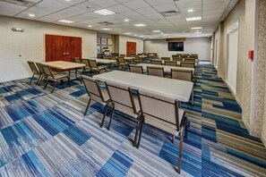 A conference room with multiple tables and chairs, carpeted floors, and a flat-screen TV mounted on the wall. - Holiday Inn Express Hotel & Suites Cookeville by IHG (Cookeville)
