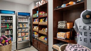 A convenience store with refrigerated sections, shelves stocked with snacks and beverages, and a display of hats and merchandise. - Hampton Inn Knoxville East (Knoxville)