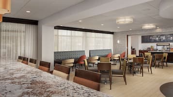 A modern dining area with a long marble counter and multiple seating options including booths and chairs.