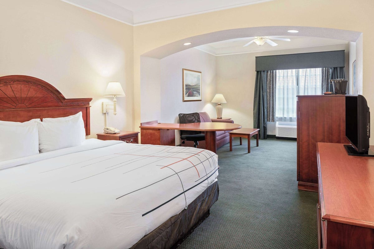 Une chambre d’hôtel avec un grand lit, un bureau avec une chaise, une télévision et une lampe de bureau.