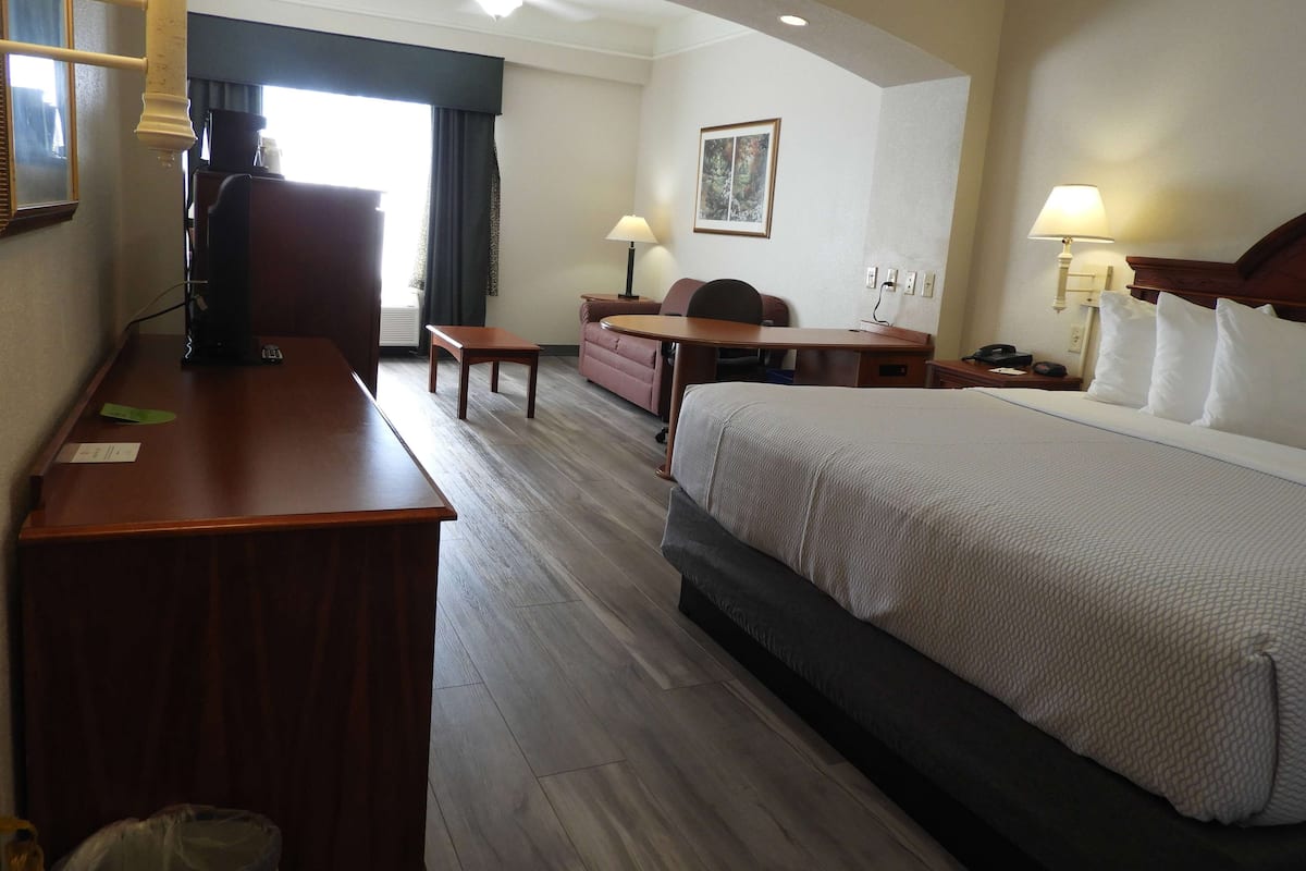 Une chambre d’hôtel avec un lit, un bureau, une chaise et une petite table.