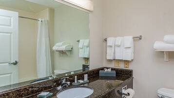 Un baño con lavamanos, espejo, toallero y retrete.