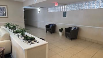 A reception area with a reception desk, two armchairs, a potted plant, and a wall-mounted sign.