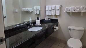 A bathroom with a black marble sink, white toilet, and towel racks. - Stay Well Inn & Suites (Fort Myers)