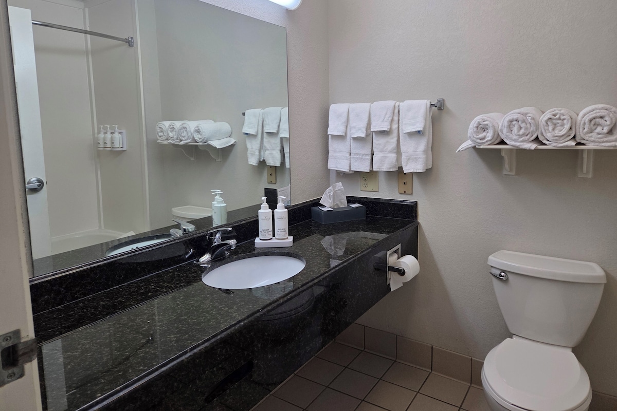 A bathroom with a black marble sink, white toilet, and towel racks.