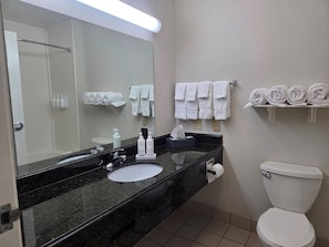 A bathroom with a black marble sink, white toilet, and towel racks. - Stay Well Inn & Suites (Fort Myers)