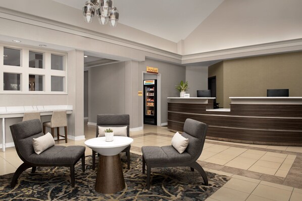 A lobby with a reception desk, two armchairs, a small table, and a plant. - Residence Inn by Marriott Fayetteville Cross Creek (Fayetteville)