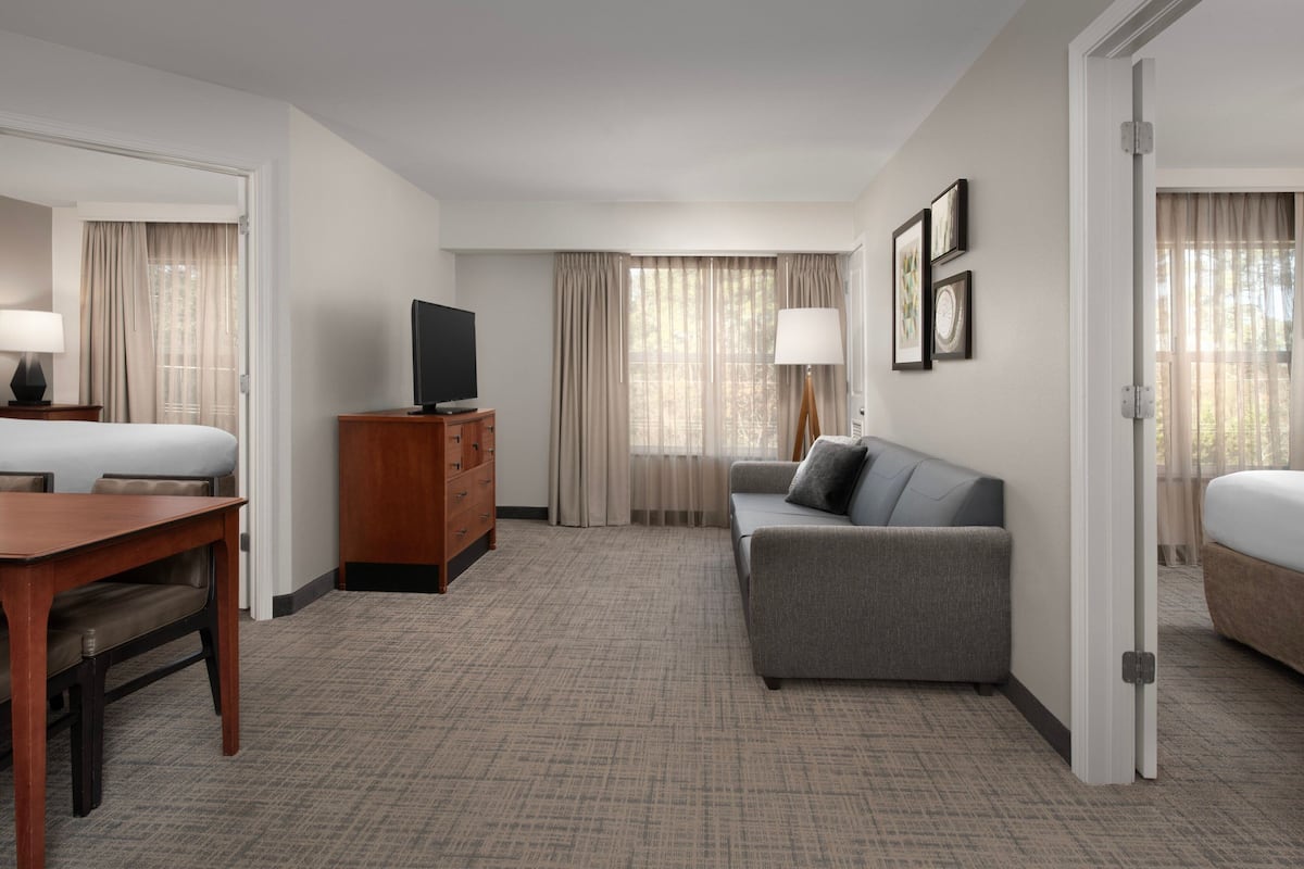 Una habitación de hotel con cama, sofá, televisor, escritorio y cómoda.