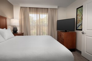 A hotel room with a large bed, a television on a wooden dresser, and a window with curtains. - Residence Inn by Marriott Fayetteville Cross Creek (Fayetteville)