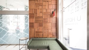 A modern hotel lobby with a wooden wall panel, a green sofa, and a small round table.