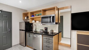 A modern kitchen with stainless steel appliances, wooden shelves, and a built-in TV.