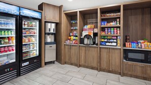 A kitchenette area with a refrigerator, microwave, and coffee machine.